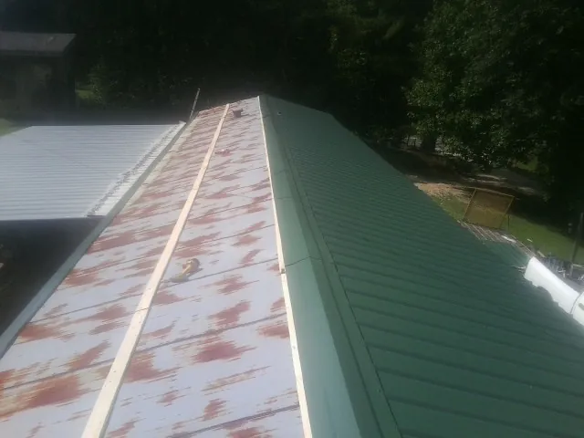 Old rusted panels beside newly installed green metal roofing — Wind Damage Roof Repair by Roofing Brothers in Mercer