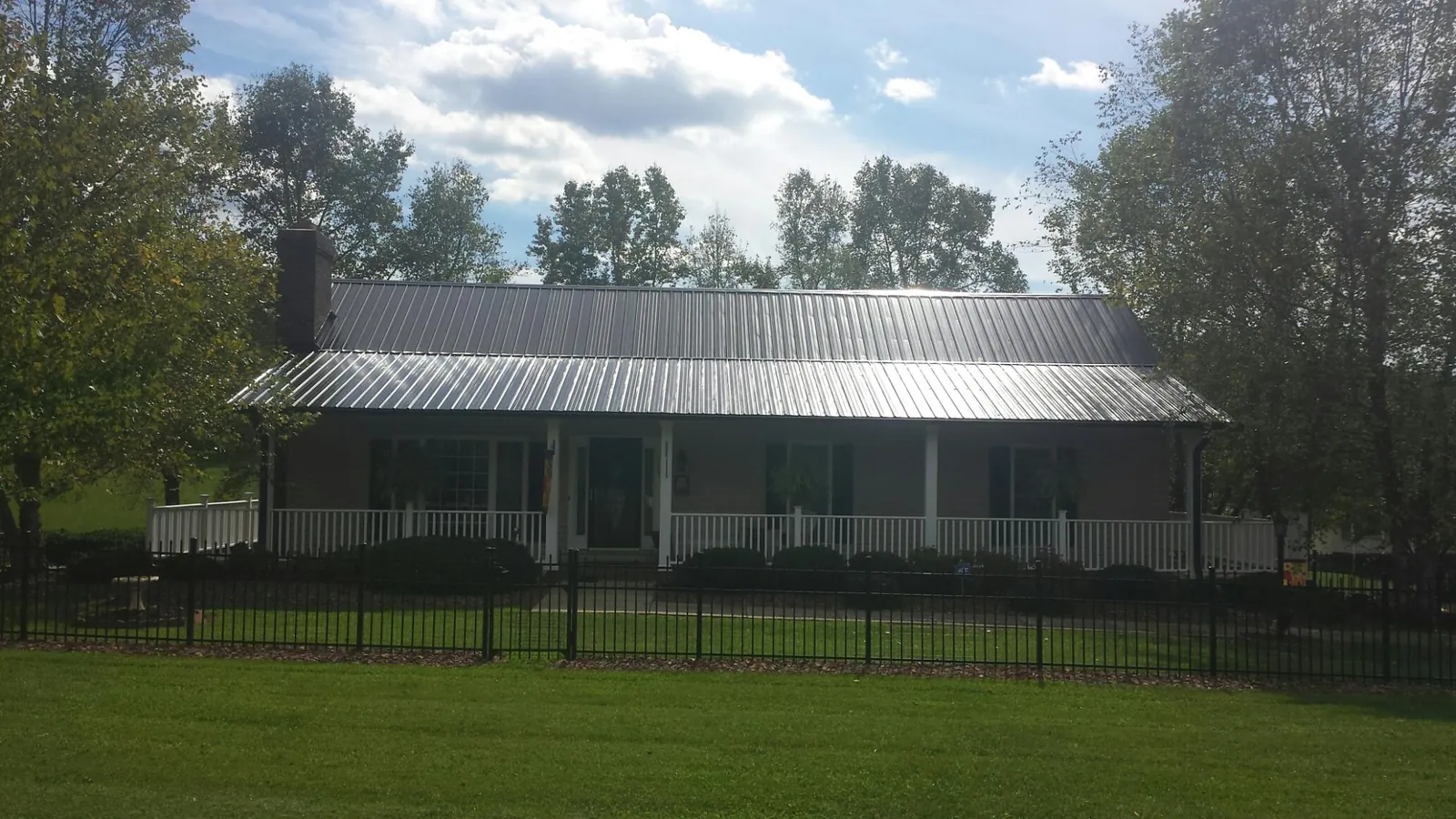 Gray metal roof on a brick ranch with a full width front porch — Gutter Guard Installation work by our crew in Mercer