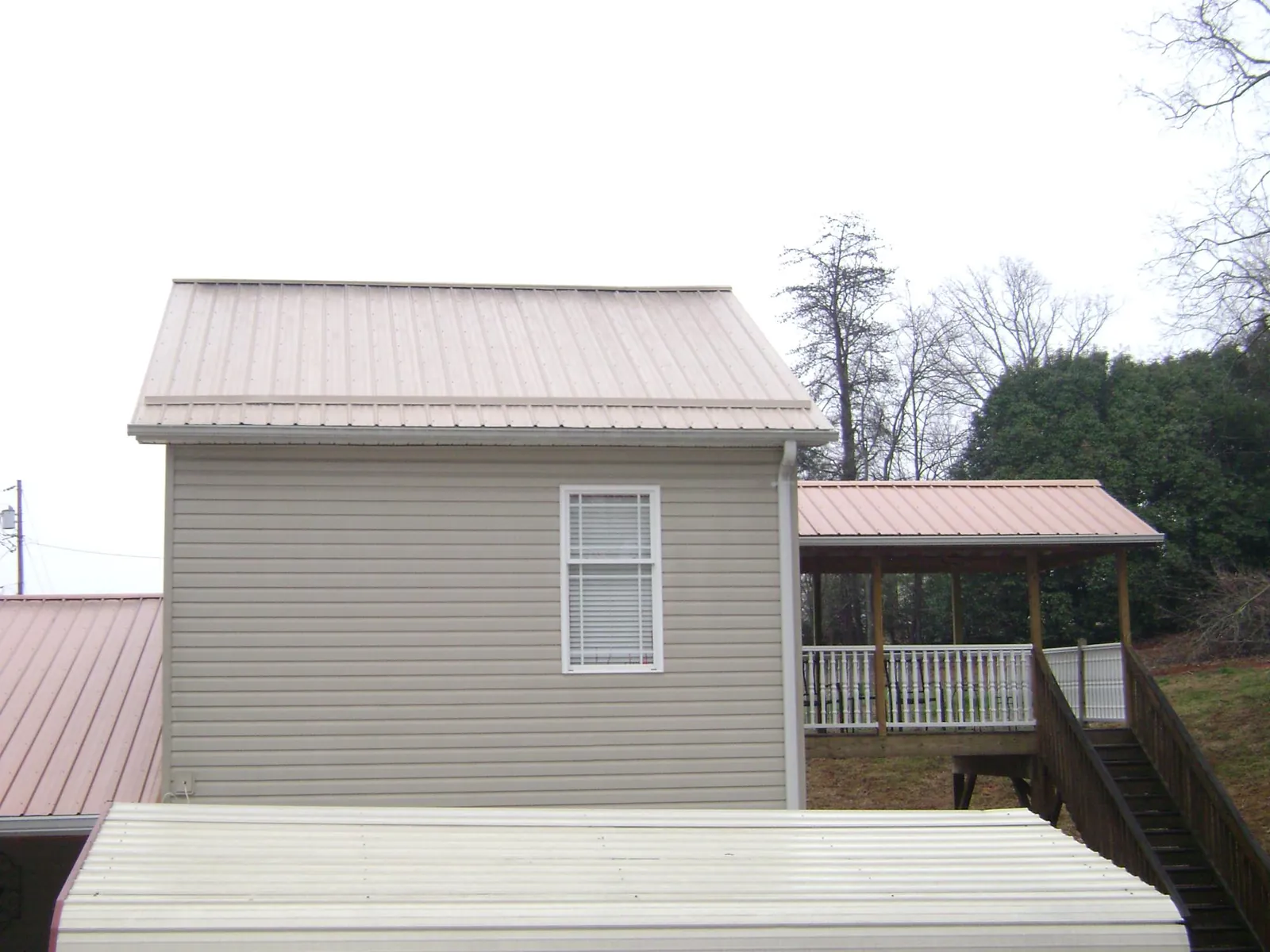 Tan metal roofs on a two story addition and attached porch, from a Roof Replacement job in Mercer
